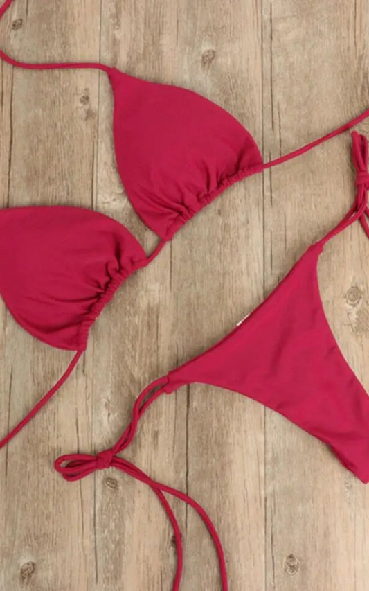 Maillot de bain rouge 2 pièces posé sur une table avec un bas échancré et un haut classique 